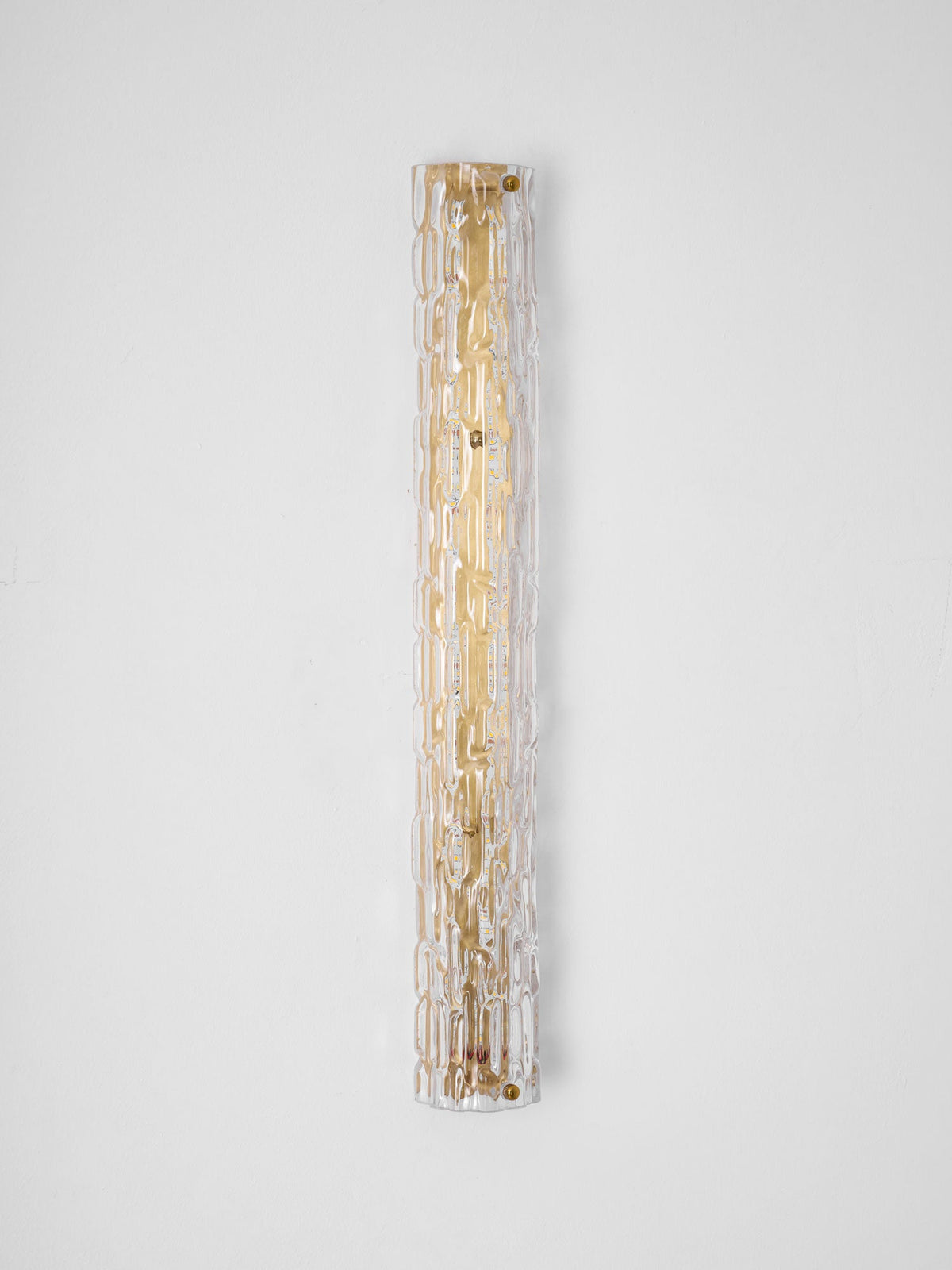 Full-length view of a Clérachic wall light on a pale wall, the clear rippled glass over a gold backplate with brass screws.