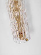 Close view of the bottom end of this Clérachic wall light, with rippled glass, gold backplate and a brass screw.