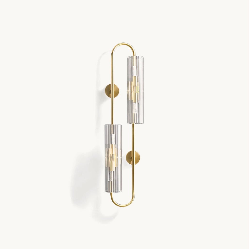 Brass wall light from Clérachic with two ribbed clear glass tubes on an elongated looped frame, unlit on a plain white backdrop.