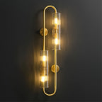 Lit close up, the ribbed glass tubes of this Clérachic brass wall light throw a warm glow across a dark wall from a looped brass frame.