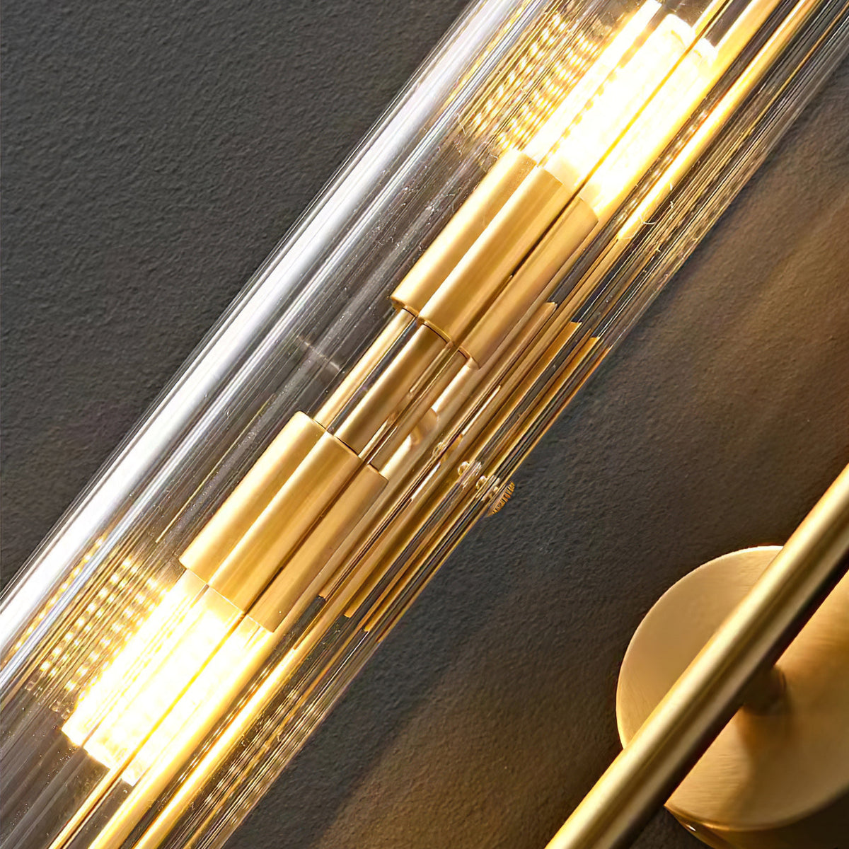 Diagonal close view of the ribbed glass and brass inner fittings of this Clérachic wall light, with the lit bulbs glowing warm.