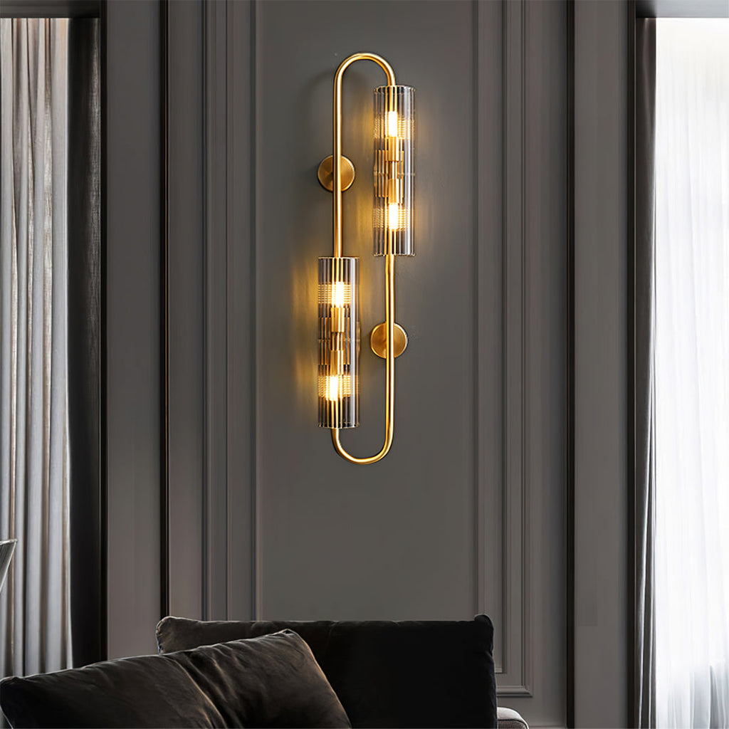 A Clérachic double glass wall light lit on a dark panelled wall above a black sofa, with sheer curtains at the window edge.