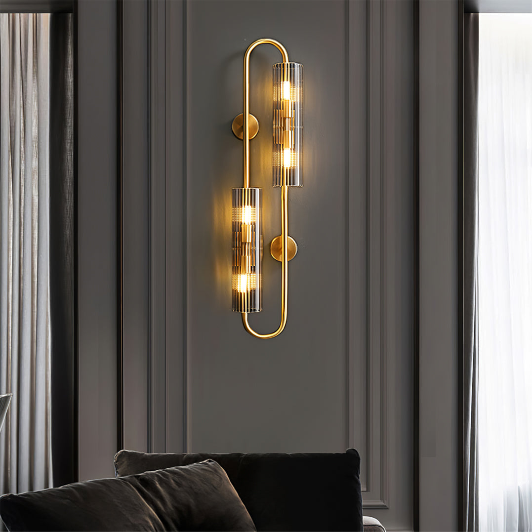 A Clérachic double glass wall light lit on a dark panelled wall above a black sofa, with sheer curtains at the window edge.