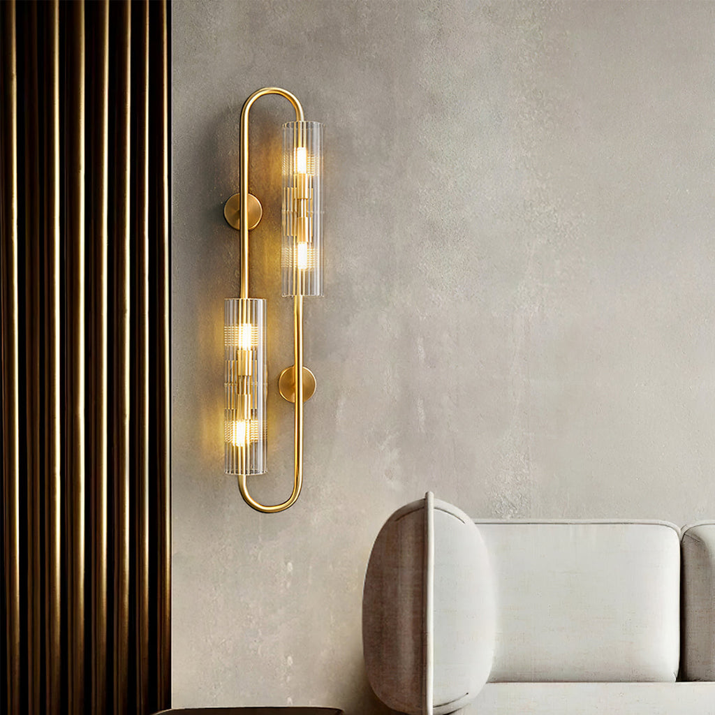 Against a pale plaster wall, this Clérachic brass wall light glows beside a cream sofa and a wall of dark vertical slats.