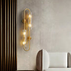Against a pale plaster wall, this Clérachic brass wall light glows beside a cream sofa and a wall of dark vertical slats.