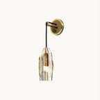 A Clérachic wall light on a plain white backdrop: a round brass backplate, a black cord arm and a faceted crystal shade with a brass socket inside.