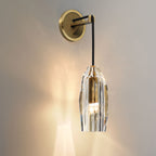Close view of this Clérachic wall light glowing warm against a soft grey wall, light spilling through the faceted crystal shade.