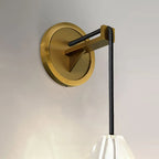 Close view of the round brass backplate and black braided cord arm on this Clérachic wall light, with the crystal shade just visible below.