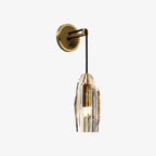 This Clérachic wall light against a pale grey backdrop, the brass round plate and crystal shade seen straight on with the bulb glowing.