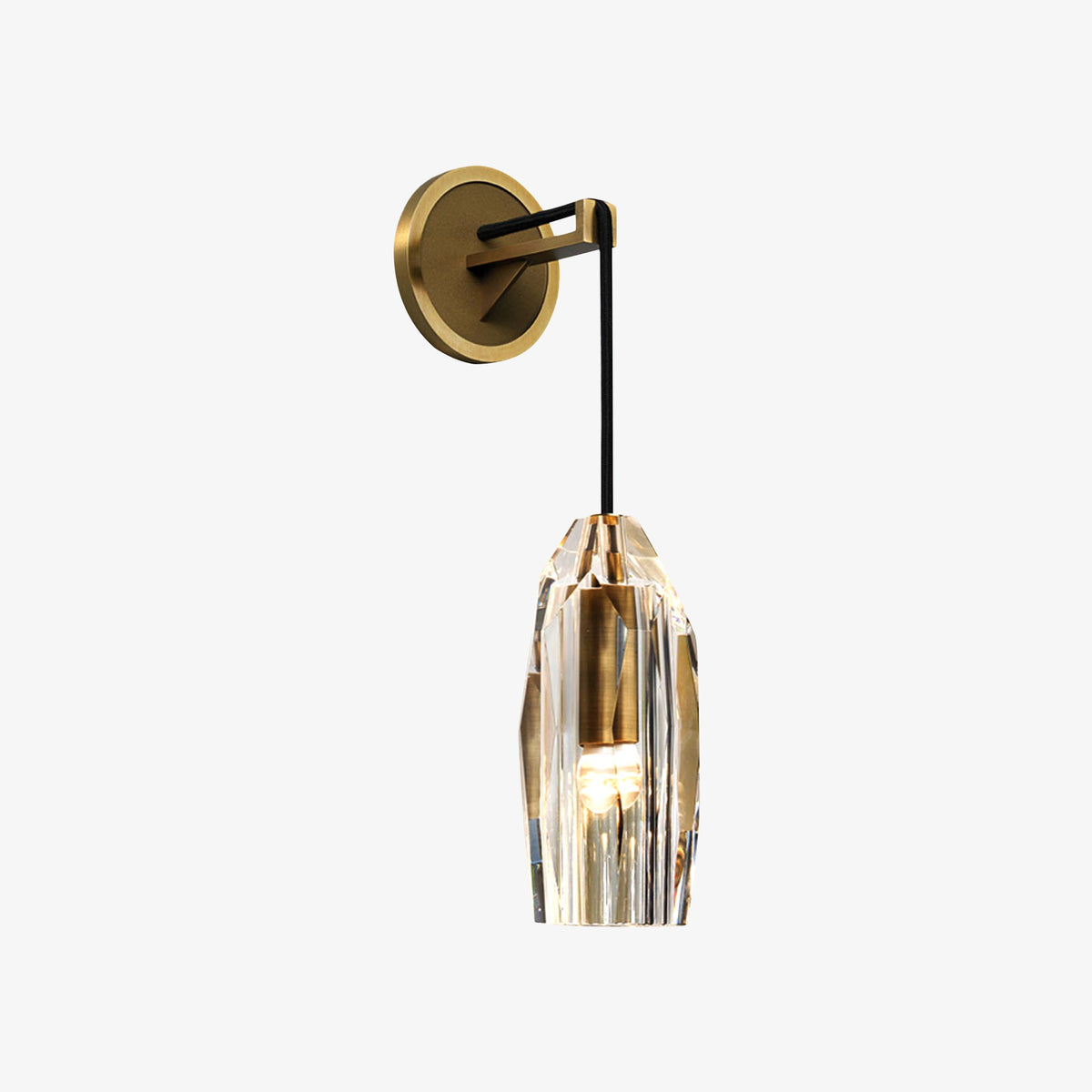 This Clérachic wall light against a pale grey backdrop, the brass round plate and crystal shade seen straight on with the bulb glowing.