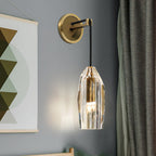 This Clérachic wall light lit against a blue-grey wall, beside a grey-green curtain and a geometric print in olive and cream.