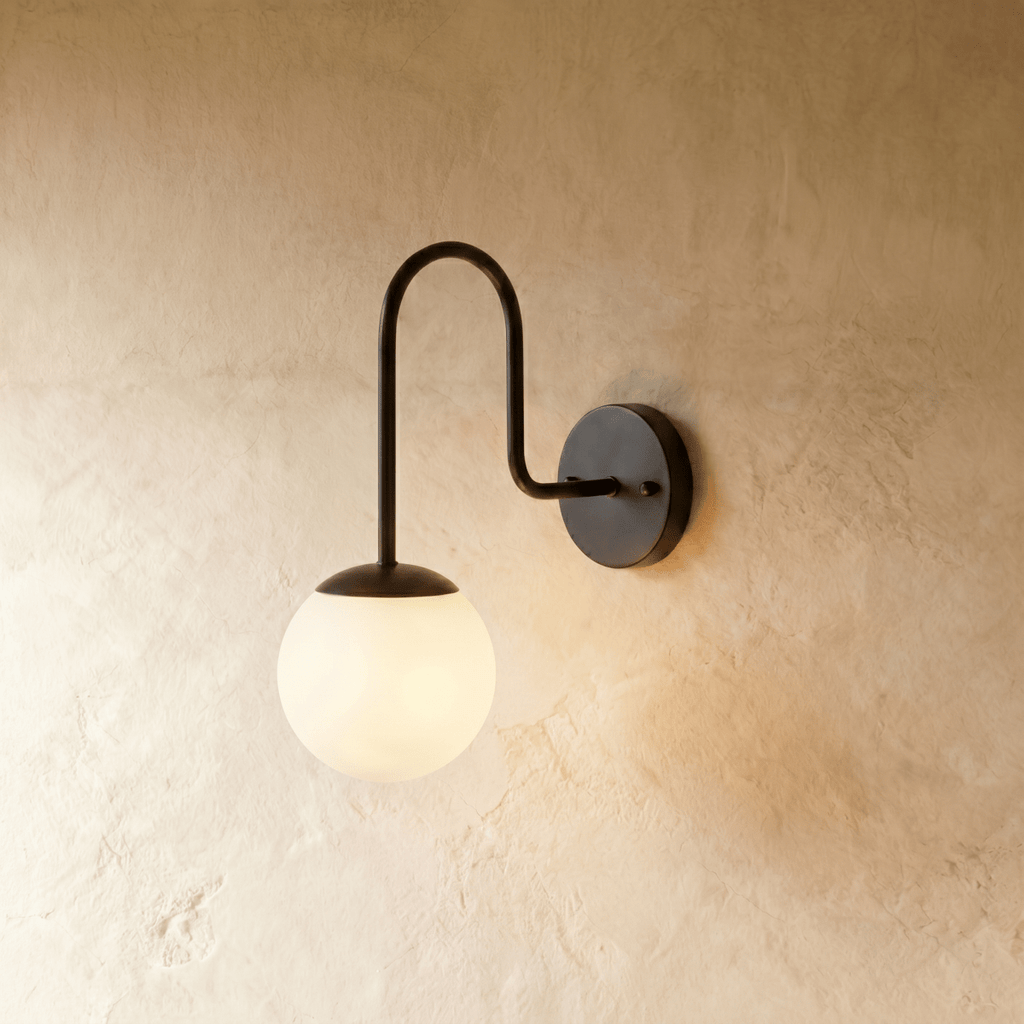 Clérachic wall lamp in matte black, a frosted glass globe glowing beneath a curved gooseneck arm.