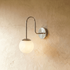 Clérachic wall lamp in chrome shown close, the frosted glass globe catching a cool metallic sheen.