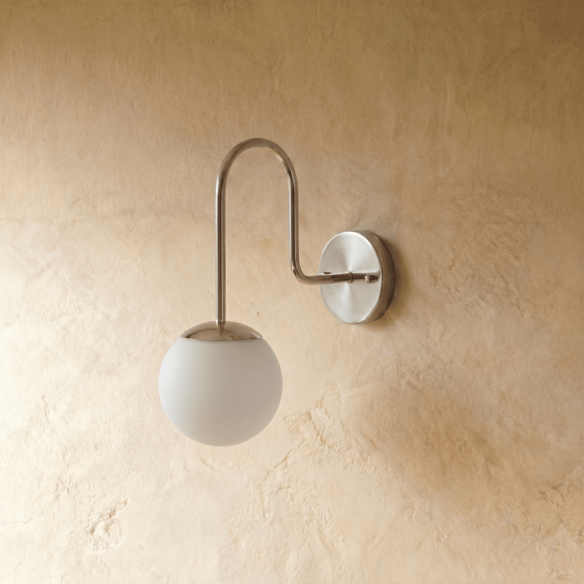 Clérachic wall lamp in chrome viewed at an angle, the gooseneck arm curving toward the glass globe.