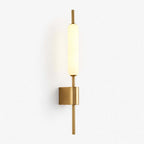Slim brass wall sconce from Clérachic with a frosted glass tube, lit warm white on a plain white backdrop.