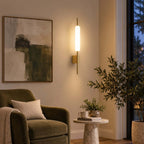 Beside an olive-green armchair and an abstract painting, this Clérachic brass wall sconce glows warm in the evening light.