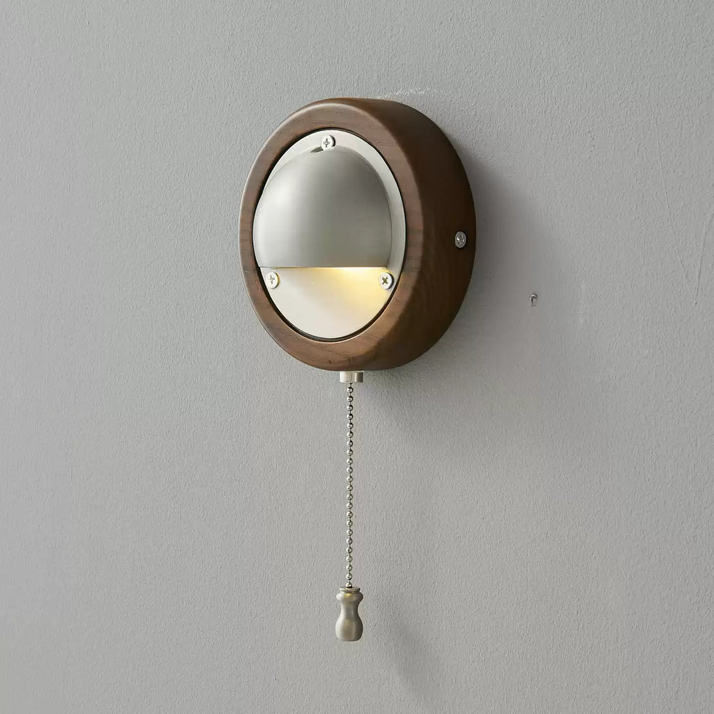 A round Walnut & Silver Clérachic wall light with a silver half-dome shade and a beaded pull chain, on a plain grey wall.