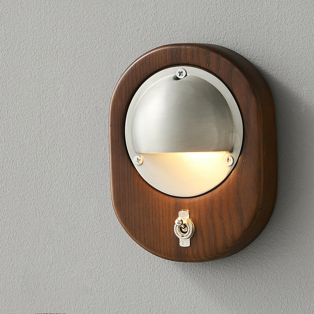 Taller Model B Clérachic wall light in Walnut & Silver, with an oval walnut frame, a lit silver half-dome and a toggle switch below.