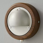 Close view of the round walnut frame, silver half-dome and screw heads on this Clérachic wall light in Walnut & Silver.