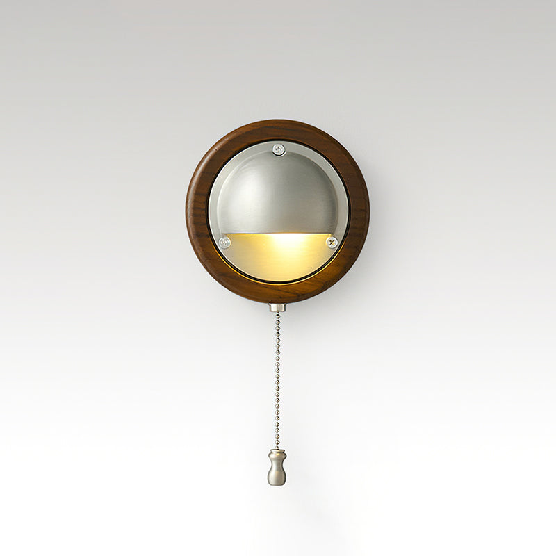 Round Walnut & Silver Clérachic wall light with a lit half-dome and a chain pull, on a soft grey studio backdrop.