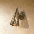 Clérachic wall lamp in vintage brass with a perforated cone shade casting warm striped light on the wall.
