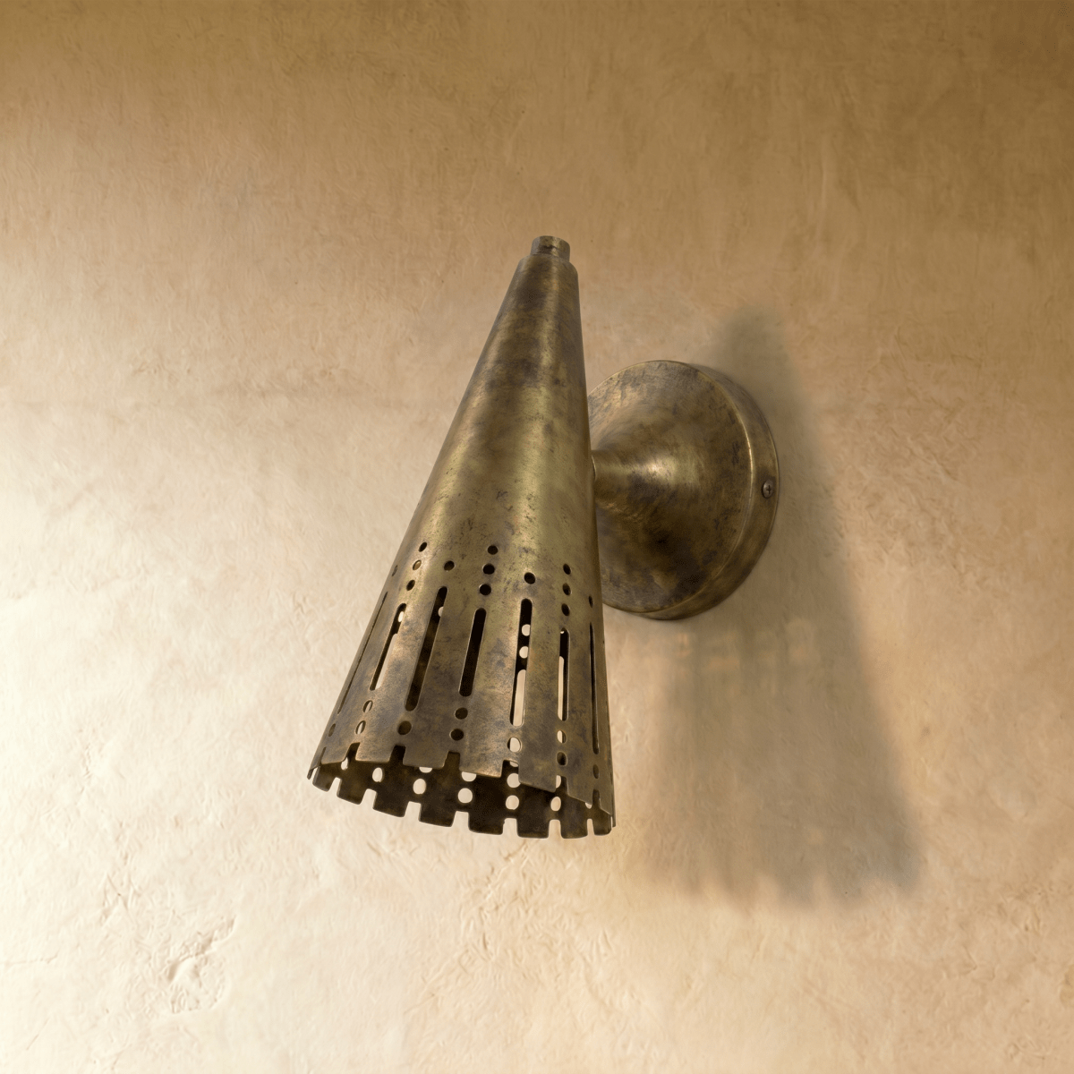 Clérachic wall lamp shown in vintage brass, its slotted cone shade angled to direct light downward.