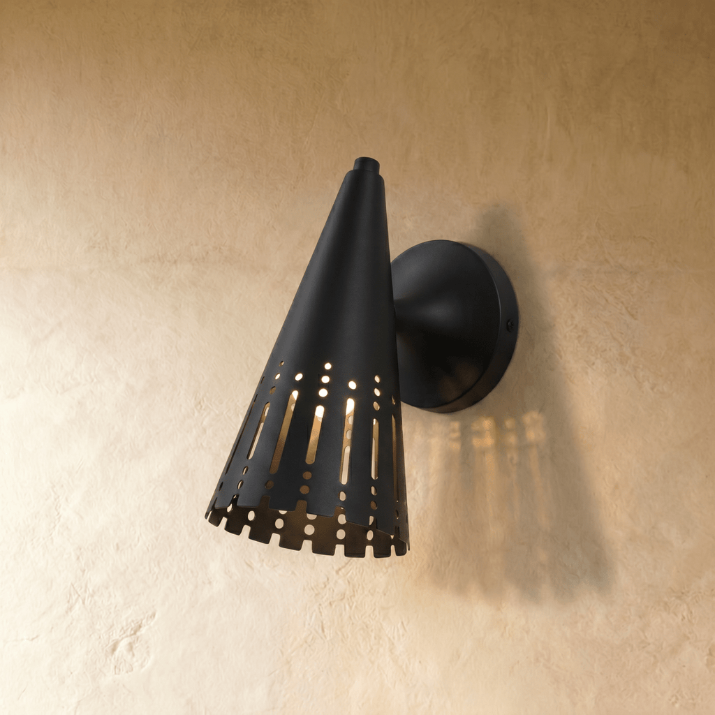 Clérachic wall lamp in matte black, a slotted cone shade throwing warm striped light across the wall.