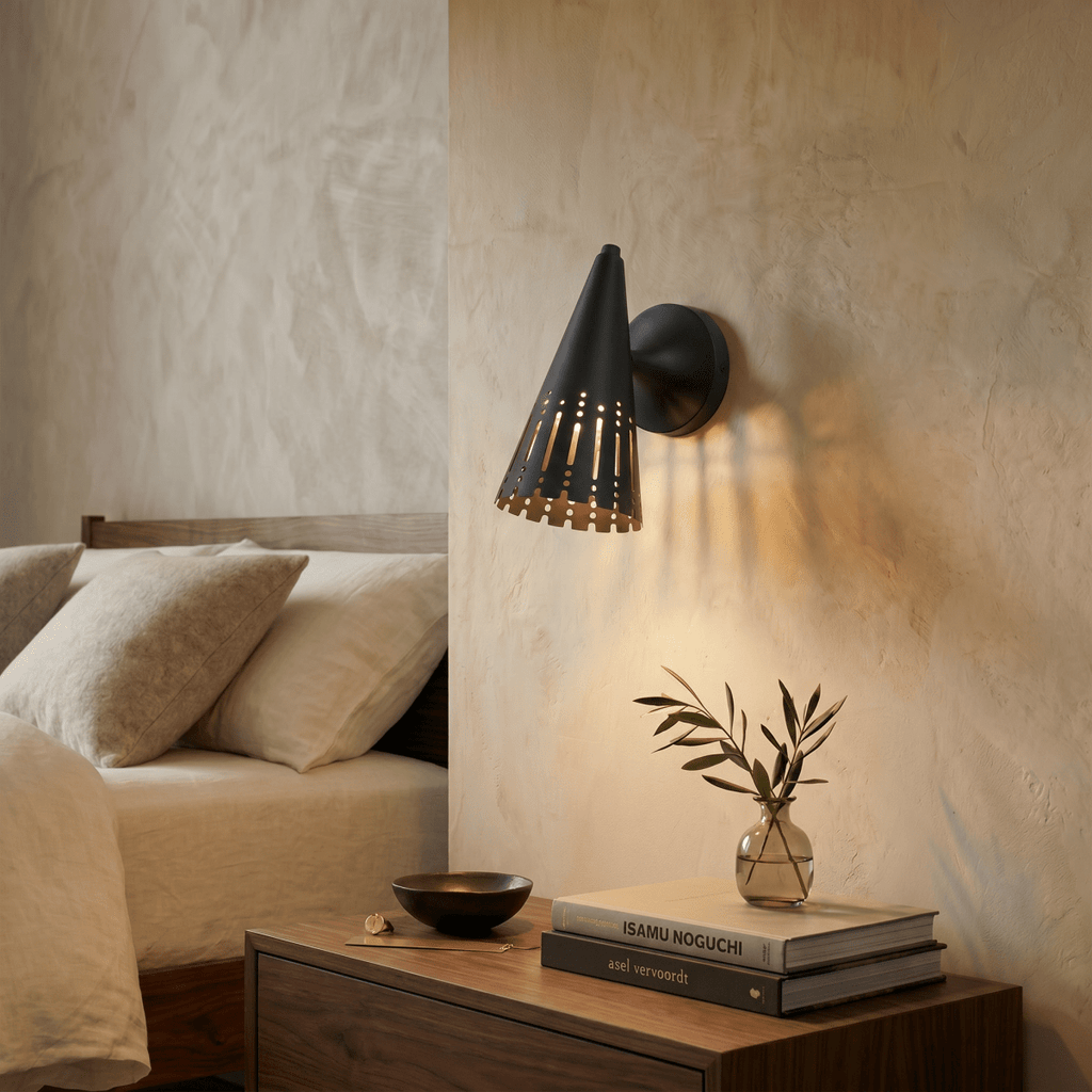 Clérachic wall lamp in matte black above a walnut nightstand with stacked design books and a small vase.