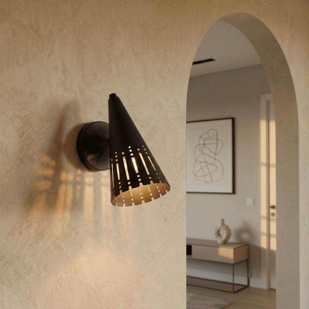 Clérachic wall lamp in matte black lighting a plaster hallway wall beside an archway into the living room.
