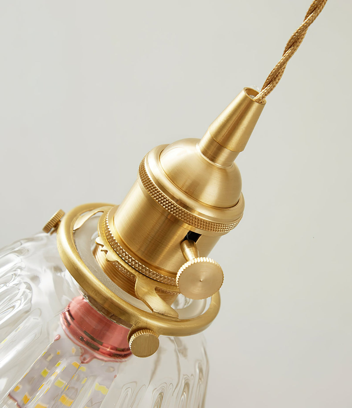 Close view of the brass socket, knurled collar and twisted cord at the top of this Clérachic wall light.