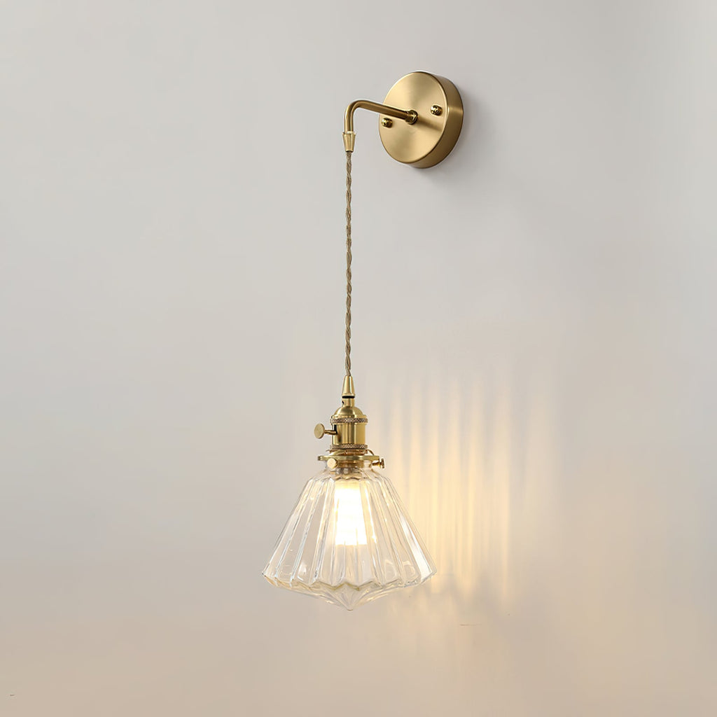 A Clérachic wall light lit on a light grey wall, its glass shade throwing vertical streaks of warm light to one side.