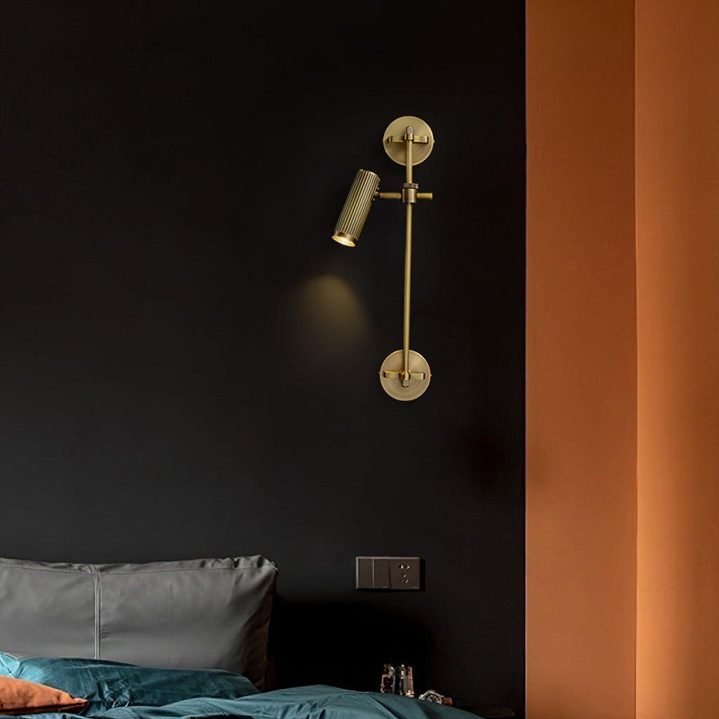 One lit spot head on a slim bronze rail, from Clérachic, hung on a dark wall above a bed with teal bedding, beside an orange wall.