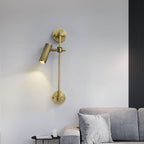 A single lit spot head on a bronze rail, from Clérachic, mounted on a pale wall above a grey sofa with a small black side table.