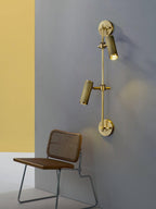Two-head wall light from Clérachic on a grey-blue wall with a yellow panel, with each head aimed down above a cane-backed chair.