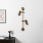 Two-head wall light from Clérachic in bronze, unlit, on a white wall with a framed line drawing and a candle on a dark table.