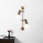 Two-head Clérachic wall light on a white wall, lit with a soft pool of light under each head, above a black candlestick.
