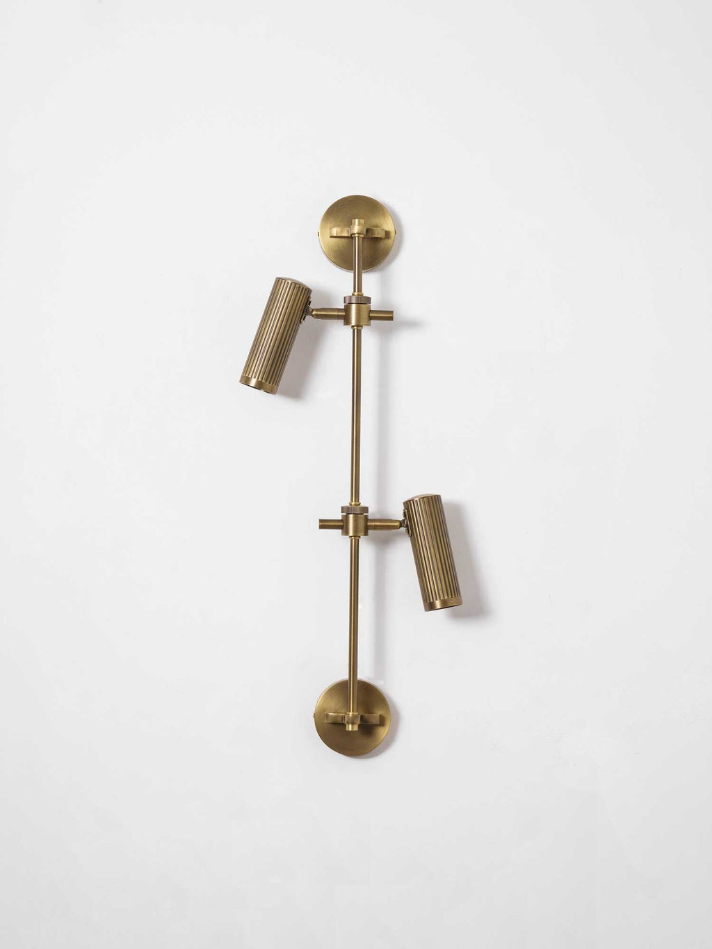 Two fluted bronze heads and a round backplate on a vertical rail from Clérachic, seen against a plain white wall.