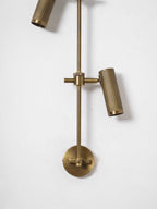 Detail of the lower head, rail and round bronze backplate on this Clérachic wall light, on a white wall.