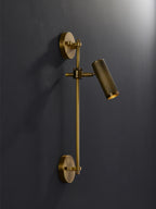 Single-head bronze wall light from Clérachic, unlit, on a dark charcoal wall with its round backplate at both ends of the rail.
