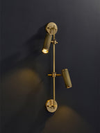 Two-head Clérachic wall light on a dark wall, with the upper head lit and aimed down and the lower head angled out.
