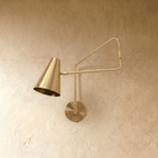 Clérachic wall lamp in brushed brass shown from another angle, the swing arm extended from the wall.