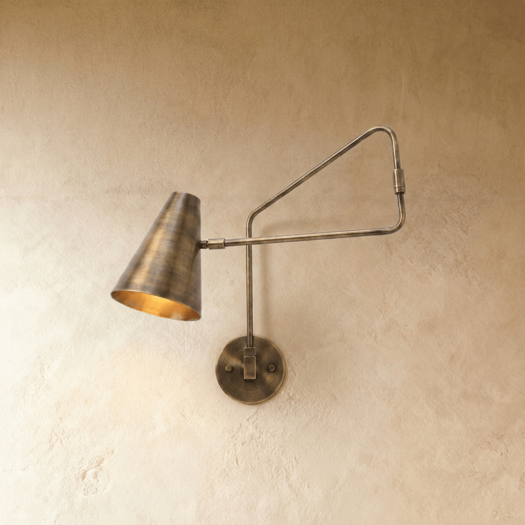 Clérachic wall lamp in vintage brass, a cone shade on an articulated swing arm against plaster.
