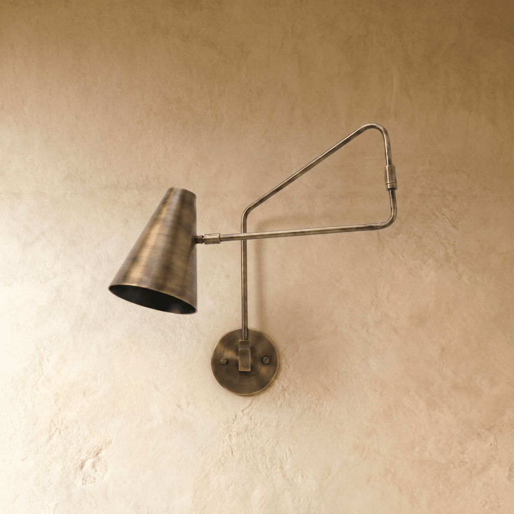 Clérachic wall lamp in vintage brass shown close, the jointed arm angled toward the cone shade.