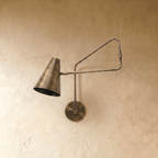 Clérachic wall lamp in vintage brass shown close, the jointed arm angled toward the cone shade.