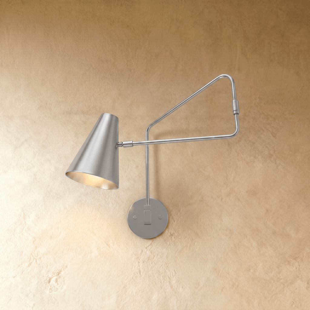 This Clérachic wall lamp in chrome, a cone shade on an articulated swing arm against plaster.