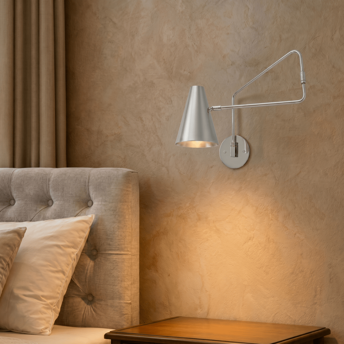 Clérachic wall lamp in chrome above a tufted headboard, its swing arm reaching over the nightstand.