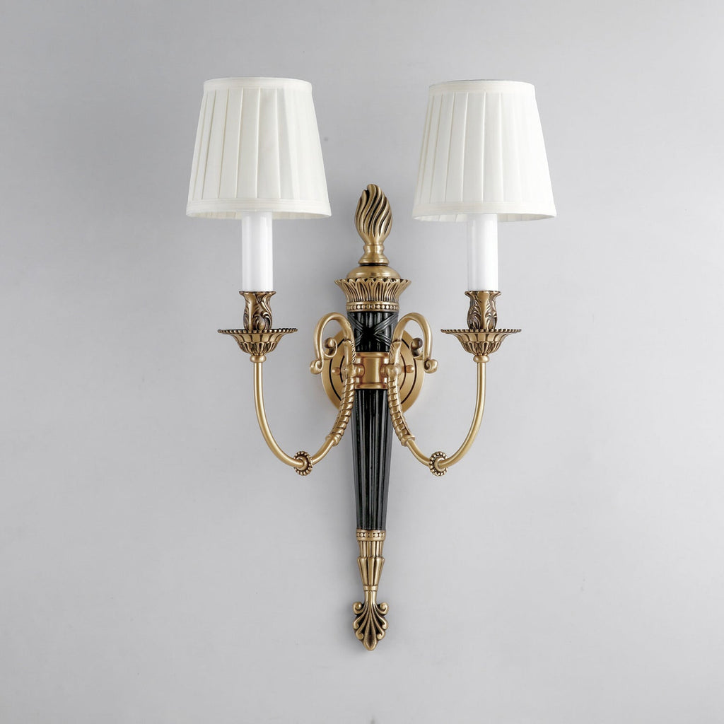 Unlit pleated white shades sit on candle-style holders on this Clérachic wall light, mounted on a pale grey wall.