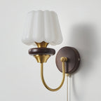 Unlit fluted white glass shade on a Clérachic wall lamp, with a brass cup, a walnut ring and a curved brass arm.