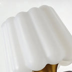 Close view of the ribbed white glass shade of this Clérachic wall lamp, with the brass cup beneath it.