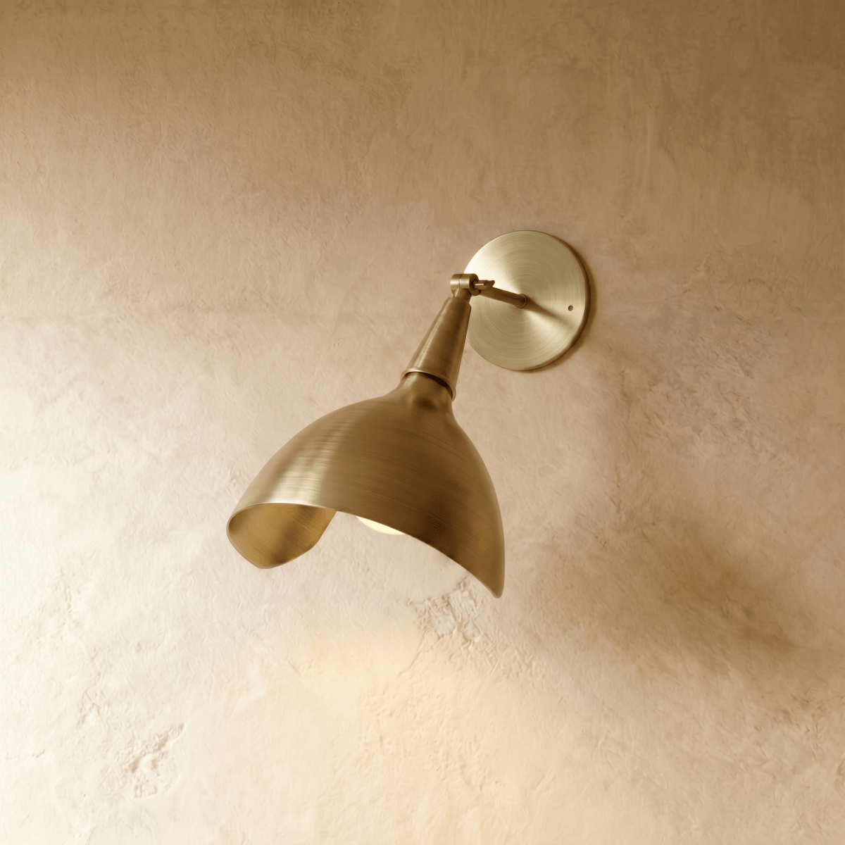 Clérachic wall lamp in brushed brass, the angled cone shade poised to direct light downward.